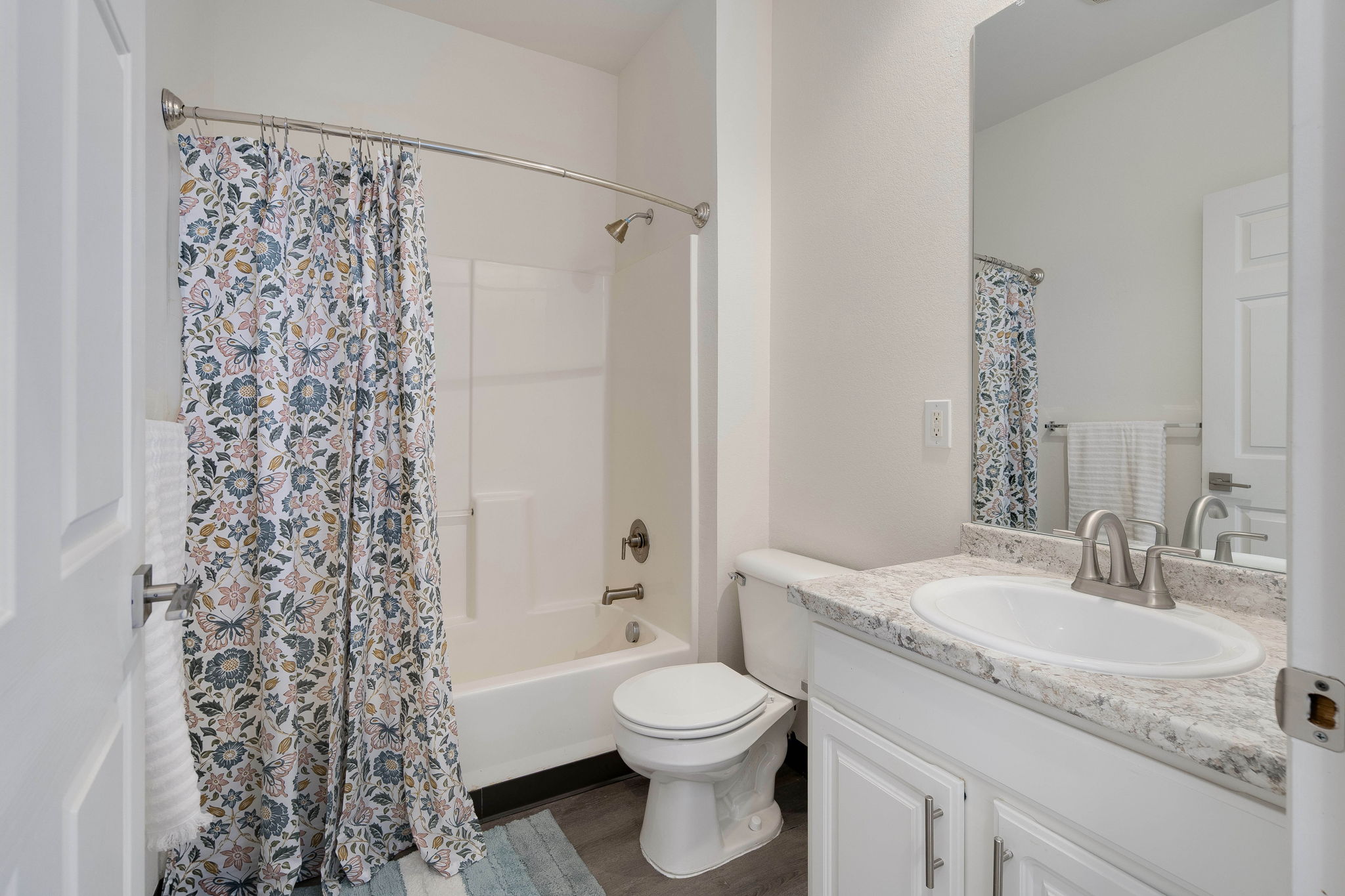 A white bathroom with a floral shower curtain.
